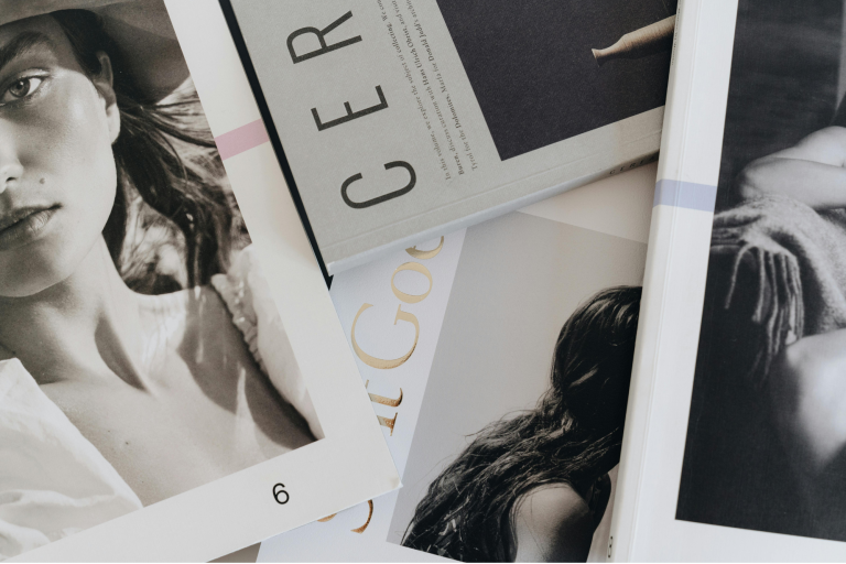 Open luxury fashion and lifestyle magazine displaying editorial typography, photography grids, and a striking gold foil accent layout.