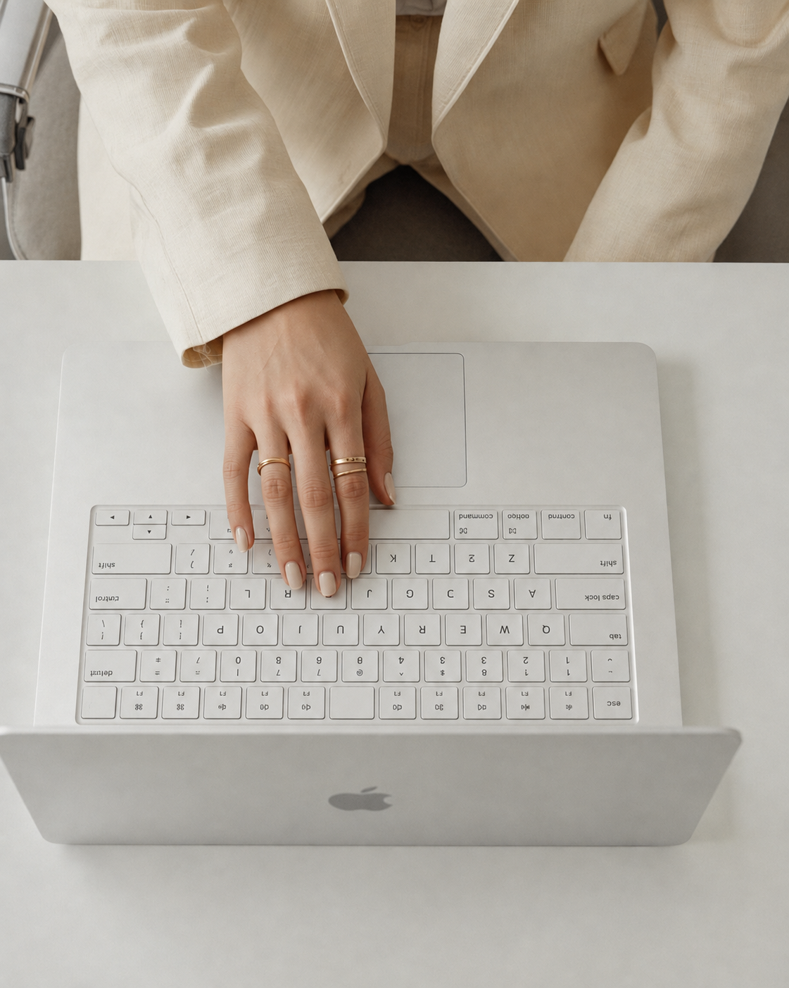 Hand resting on a laptop keyboard in a neutral workspace